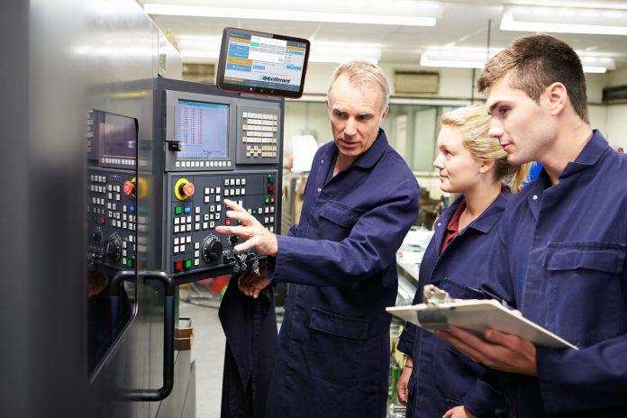Engineer Teaching Apprentices To Use Computerized Lathe
